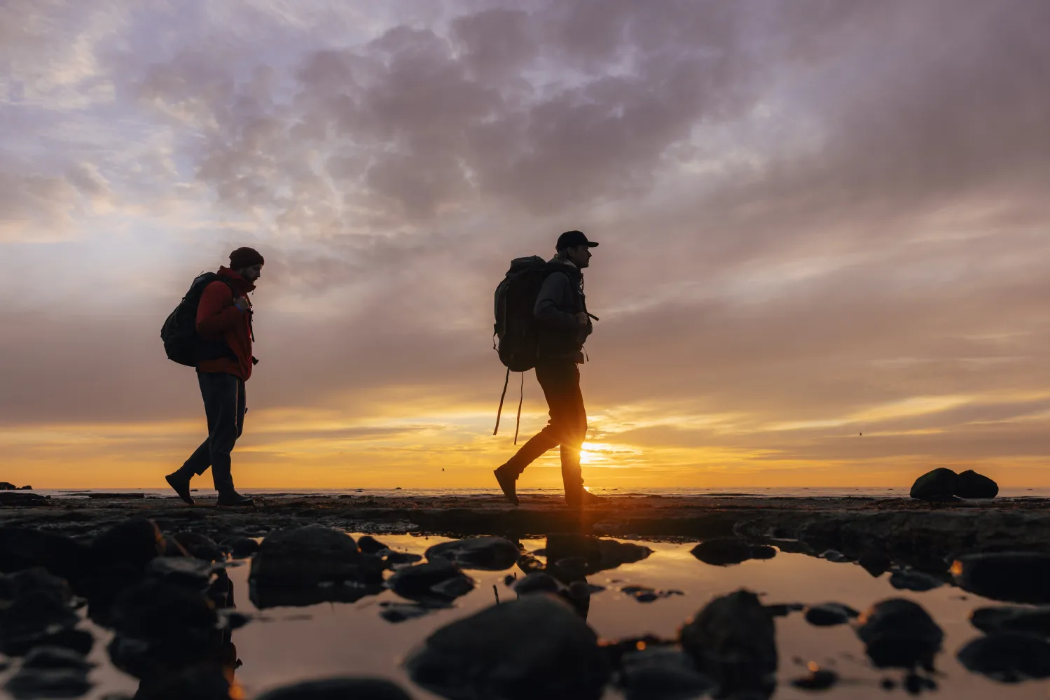 Två män som vandrar längs med kusten på Öland i solnedgång.
