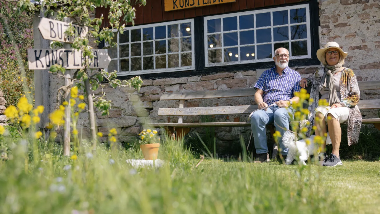 Ett par vilar på en bänk utanför en konstlada
